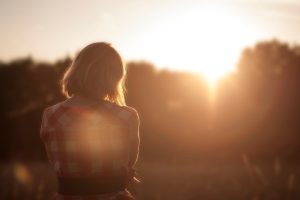 woman faced away from camera amongst the trees at sunset