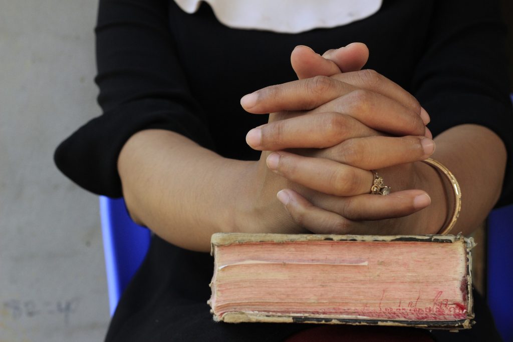 clasped hands on book
