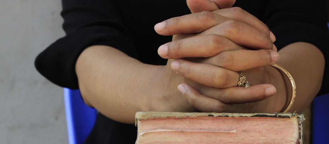 clasped hands on book