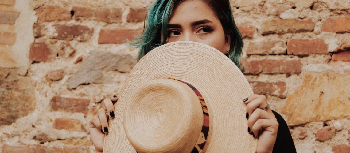 woman hiding face with hat embarrassed for not keeping resolutions
